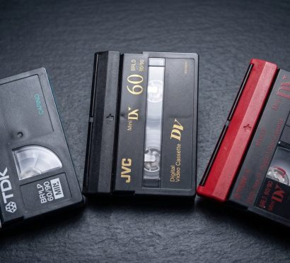 Три кассеты MiniDV разных производителей на тёмном фоне