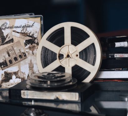 Бобина киноплёнки и футляр с киноплёнкой на тёмном фоне