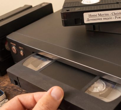 Загрузка кассеты в видеомагнитофон крупным планом, кассета с надписью Home Movies Christmas 97
